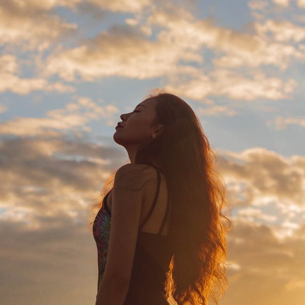 Person meditating peacefully outdoors during a beautiful sunrise.